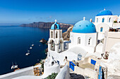 Weiße gewaschene Steingebäude und die blauen Kuppeln einer Kirche in Oia, Santorini, Kykladen, griechische Inseln, Griechenland, Europa