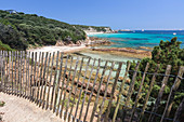 The wooden fence frames the limestone rocks and turquoise sea, Sperone, Bonifacio, South Corsica, France, Mediterranean, Europe