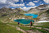 Hikers pass the turquoise lake and rocky peaks, Joriseen, Jorifless Pass, canton of Graubunden, Engadine, Switzerland, Europe
