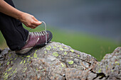 Detail of climber lacing up rock boots before climb