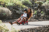 Eine Frau mit ihrem Sohn genießen die Fahrt auf einem Spielzeugauto