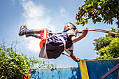 'Ein junges Mädchen, das mitten in der Luft schwingt; Kampala, Uganda'