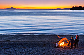 People enjoying a campfire on the beach at sunset, Hesketh Island, Southcentral Alaska, USA