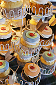 Cupcakes in a tiered holder decorated with layers of icing and feathers
