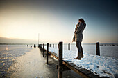 woman on a jetty on frozen Lake Starnberg, Ambach, upper Bavaria, Bavaria, Germany