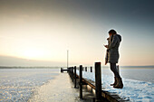 Woman on a jetty of frozen Lake Starnberg, Ambach, upper Bavaria, Bavaria, Germany