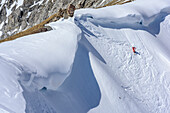 Person backcountry skiing descending through steep, corniced cirque, Hoellkar, Felskarspitze, Radstadt Tauern, Carinthia, Austria
