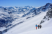 Three persons backcountry skiing ascending towards Grundschartner, Hochgall in background, Grundschartner, Zillertal Alps, Tyrol, Austria