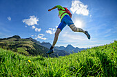 Woman trail running crossing meadow, Mitterberg, Bavarian Alps, Upper Bavaria, Bavaria, Germany