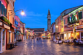 Straße mit Straßenrestaurants bei Nacht und Kirche im Hintergrund, Burano, bei Venedig, UNESCO Weltkulturerbe Venedig, Venetien, Italien