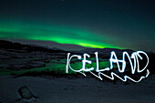 'Mit Taschenlampe geschriebener Licht Schriftzug ''Iceland'' vor Kulisse aus Landschaft mit Nordlicht bzw. Polarlicht (Aurora borealis) im pingvellir Nationalpark, Island, Iceland, Europa'