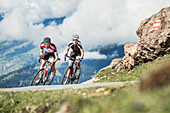 Zwei junge Menschen auf ihren Rennrädern in den Kitzbühler Alpen, Kitzbühlerhorn, Tirol, Österreich