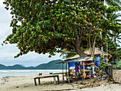 'Ein Mann steht in seinem shanty Hause am Strand entlang des Golfs von Thailand; Ko Samui, Chang Wat Surat Thani, Thailand'