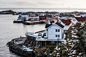 'Houses along the coastline with clouds over the ocean and horizon in the distance; Lofoten Islands, Nordland, Norway'