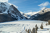 A wide angle view of Lake Louise from the upper floor of Chateau Lake Louise Resort in the winter surrounded by snow capped mountains and filled with skaters on the ice rinks carved into the frozen lake, Lake Louise, Alberta, Canada