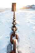 A rusty metal chain laying in the snow, Alaska, United States of America