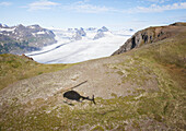 Schatten eines Hubschraubers auf einem Plateau mit Blick auf einen Gletscher und Kenai Mountains in Kachemak Bay State Park, Alaska, Vereinigte Staaten von Amerika