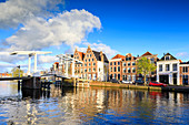 Blue sky and clouds on typical houses reflected in the canal of the River Spaarne, Haarlem, North Holland, The Netherlands, Europe