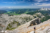 Several persons hiking ascending towards Grosser Hundstod, Steinernes Meer range, lake Zeller See and Tauern range in background, Grosser Hundstod, National Park Berchtesgaden, Natural Park Kalkhochalpen, Salzburg, Austria