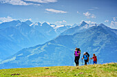 Three persons hiking at Pinzgau walk, High Tauern with Wiesbachhorn, Grossglockner and Kitzsteinhorn in background, Pinzgau walk, Kitzbuehel Alps, Salzburg, Austria