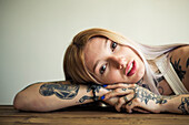 Tattooed woman resting head on arms, portrait