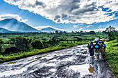 Local women carrying goods on their heads with the volcanic mountain chain of the Virunga National Park behind, after rain, Democratic Republic of the Congo, Africa