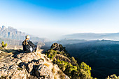 Frau genießt die Sonne am frühen Morgen auf den Klippen, Simien Mountains National Park, UNESCO Weltkulturerbe, Debarq, Äthiopien, Afrika