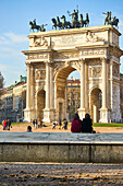 Milan, Lombardy, Italy, Girls are sitting in front the Arch of the Peace