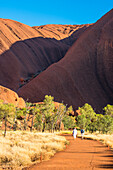 Uluru (Ayers Rock), Uluru-Kata Tjuta Nationalpark, Nordterritorium, Zentralaustralien, Australien, Zwei Menschen, die entlang des Mutihuulu Waterhole Trail spazieren
