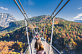 Tourists on the suspension bridge called Highline 179 framed by colorful woods in autumn Ehrenberg Castle Reutte Austria Europe