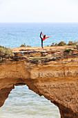 Woman practises gymnastics on the rocky cliffs Albandeira Lagoa Municipality Algarve Portugal Europe