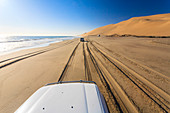 Jeep on the coast between sand dunes and the Atlantic Ocean Walvis Bay Namib Desert Erongo Region Namibia Southern Africa