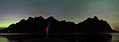 Stokksnes, Hofn, Ost-Island, Island, Ein Mann steht am Strand bei Nacht Blick auf die Nordlichter und Vestrahorn Berg