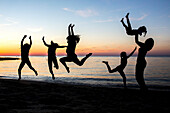 People are silhouetted jumping on a beach on Cape Cod.