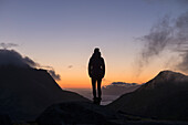 Silhouette der weiblichen Wanderer mit Blick über 3-00 am Morgen Dämmerung im Spätsommer, Moskenesøy, Lofoten Inseln, Norwegen