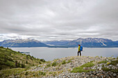 Female hiker on Monarch Mountain overlooking Atlin Lake towards the Boundary Mountain Ranges British Columbia