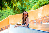 Frau sitzt am Rand des Infinity-Pool mit Kokoswasser