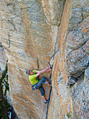 A rock climber ascending a steep crack in Medji, a climbing area close to Zermatt in the Swiss Alps.