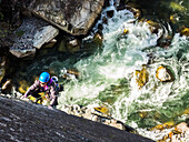 A women works her way up a rock climbing route above a river in Squamish, British Columbia.