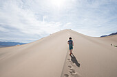 Wolken über junge zu Fuß auf Mesquite flache Sanddünen im Death Valley National Park, Kalifornien, USA