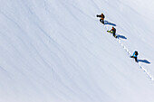 Snowboarder wandern in einer Gruppe zu einem sauberen Segeltuch des Schnees auf dem Weg zu ihren Linien