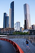 Man jogging on Enterprise Wharf with view of Southbank skyline, Melbourne.