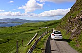 Auto auf kleiner Landstrasse an der Küste unter dem Ben More, Insel Mull, Schottland