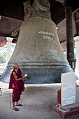 Buddhistischer Mönch schlägt die riesige Mingun Bell (die schwerste funktionierende Glocke der Welt), Mingun, Sagaing, Myanmar