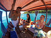 Skipper und Touristen auf Longtail-Boot während Bootsausflug zum Dorf Maung Shwe Lay, nahe Ngapali, Thandwe, Myanmar