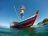 Junge Frau springt von Longtail-Boot in kristallklares Wasser während Bootsausflug zum Dorf Maung Shwe Lay, nahe Ngapali, Thandwe, Myanmar