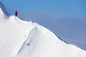 Professional snowboarder Marie France Roy, walks along a ridge line to get to her line on a sunny day in Haines, Alaska.