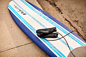 A surfboard with wetsuit gloves on the beach