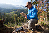 Man using portable solar energy charger with digital tablet while hiking
