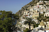 Italy, Amalfi Coast, Positano, panorama of the old fishermen village surrounded by mountains, with the Santa Maria Assunta church and its dome covered in varnished tiles, near the beach